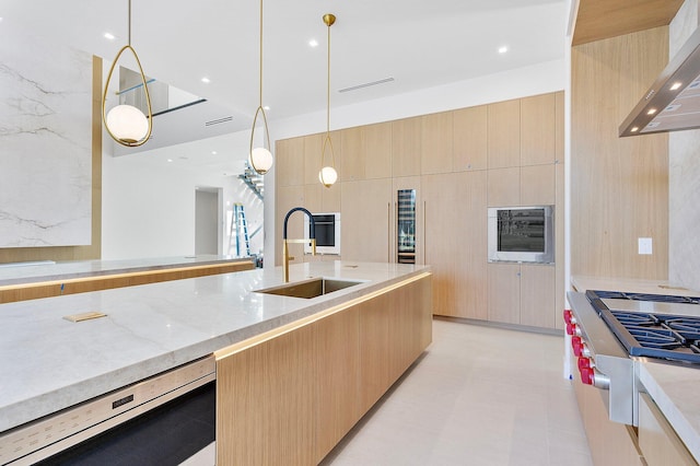 kitchen featuring dishwashing machine, sink, premium range hood, hanging light fixtures, and light brown cabinets