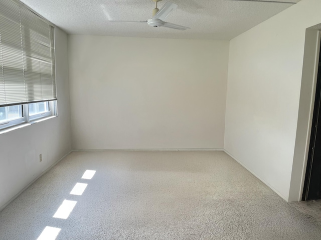 spare room featuring a textured ceiling, ceiling fan, and carpet