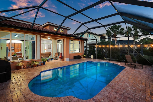 pool at dusk featuring a patio and a lanai