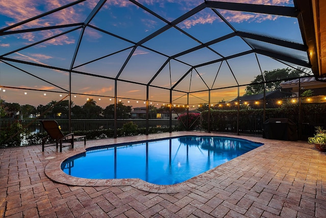 pool at dusk featuring a lanai and a patio area