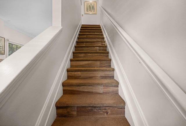 stairs featuring a decorative wall, ornamental molding, and wood finished floors
