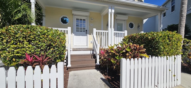 doorway to property with a wall mounted AC, a porch, and fence