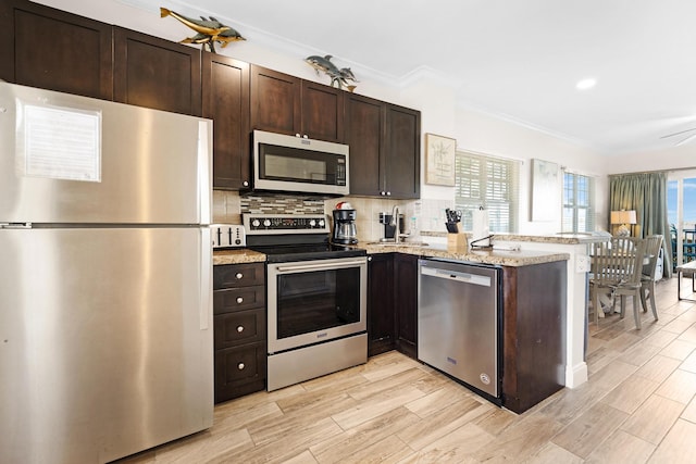 kitchen with dark brown cabinets, stainless steel appliances, backsplash, and a peninsula