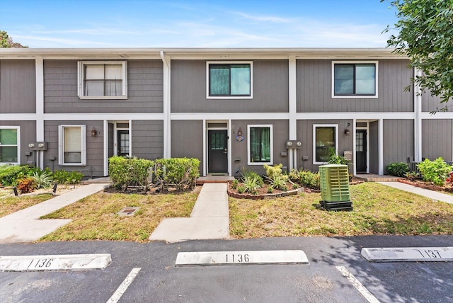 view of property featuring central AC and uncovered parking