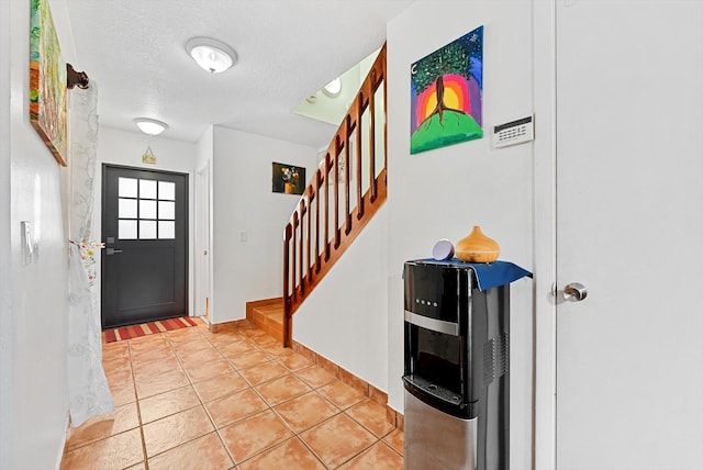 entrance foyer with light tile patterned flooring, a textured ceiling, baseboards, and stairway