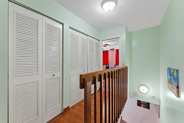 corridor with a textured ceiling and light hardwood / wood-style flooring