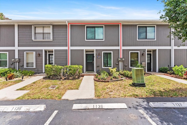 view of property featuring central AC unit and uncovered parking