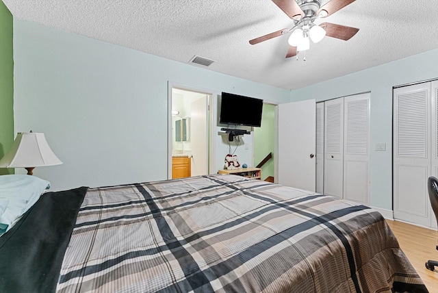 bedroom featuring multiple closets, ceiling fan, a textured ceiling, and light wood-type flooring