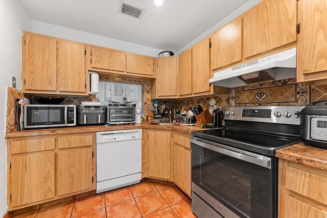 kitchen with tasteful backsplash, appliances with stainless steel finishes, sink, and light tile patterned floors