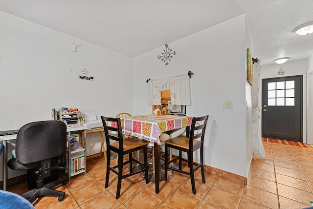 tiled dining space with a textured ceiling