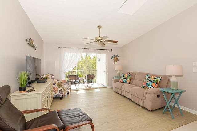 living room featuring ceiling fan, vaulted ceiling with skylight, and light hardwood / wood-style floors