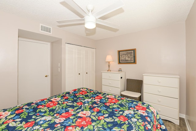 bedroom featuring ceiling fan, wood-type flooring, a closet, and a textured ceiling