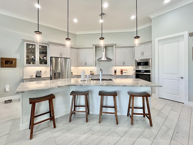 kitchen featuring decorative light fixtures, stainless steel appliances, a large island, light stone countertops, and wall chimney range hood