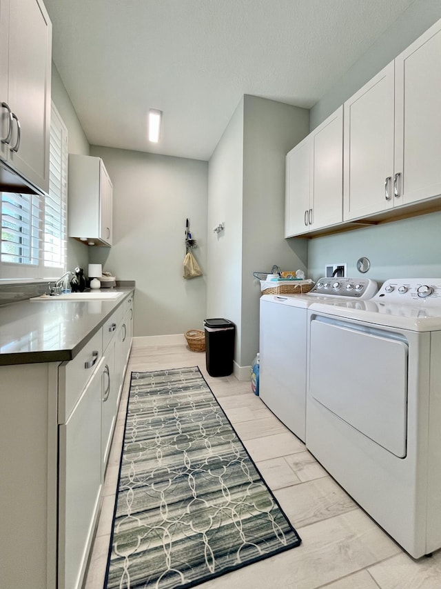 clothes washing area featuring separate washer and dryer, sink, cabinets, and a textured ceiling