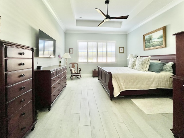 bedroom with ornamental molding, ceiling fan, light hardwood / wood-style floors, and a tray ceiling