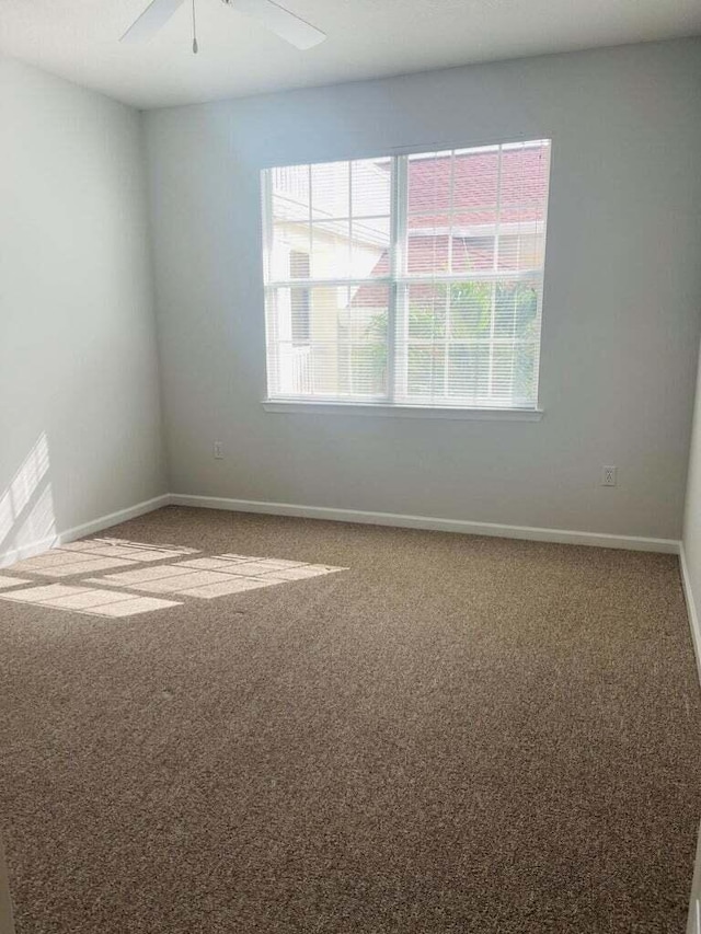 carpeted spare room featuring ceiling fan