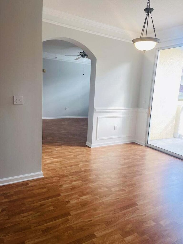 empty room featuring wood-type flooring, ornamental molding, and ceiling fan