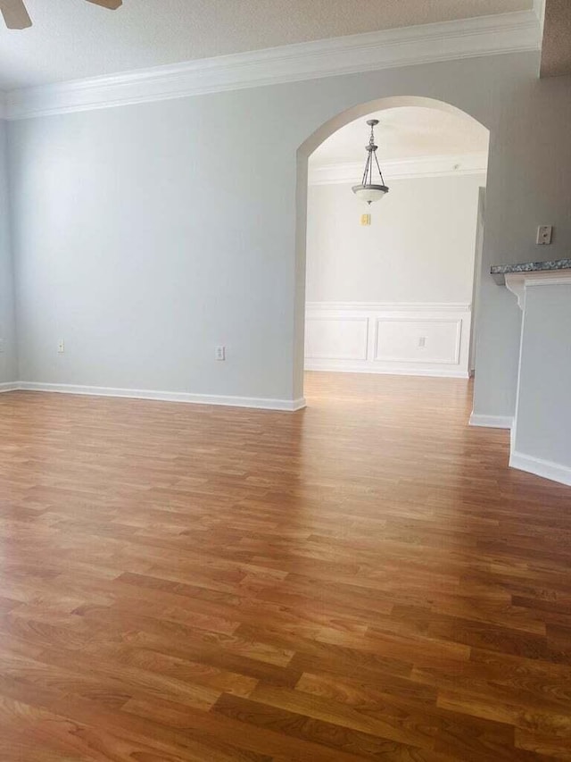 unfurnished room with hardwood / wood-style floors, crown molding, and ceiling fan