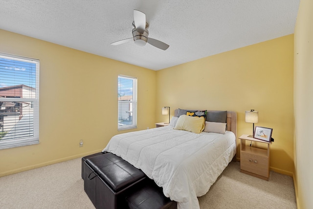 bedroom with ceiling fan, light colored carpet, and a textured ceiling