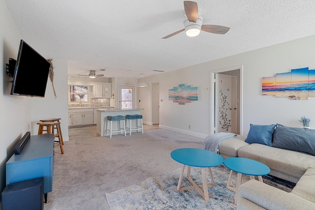 carpeted living room with sink, a textured ceiling, and ceiling fan