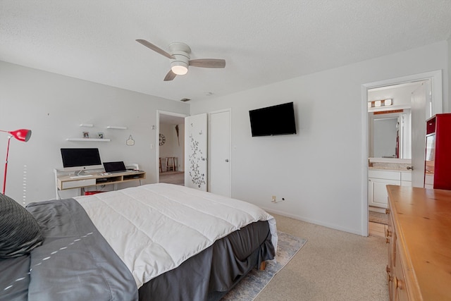 carpeted bedroom with ceiling fan, ensuite bathroom, and a textured ceiling