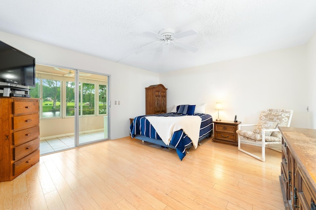 bedroom with access to outside, light hardwood / wood-style floors, and a textured ceiling