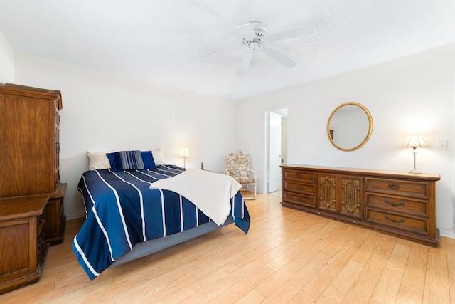 bedroom featuring ceiling fan, a textured ceiling, and light wood-type flooring