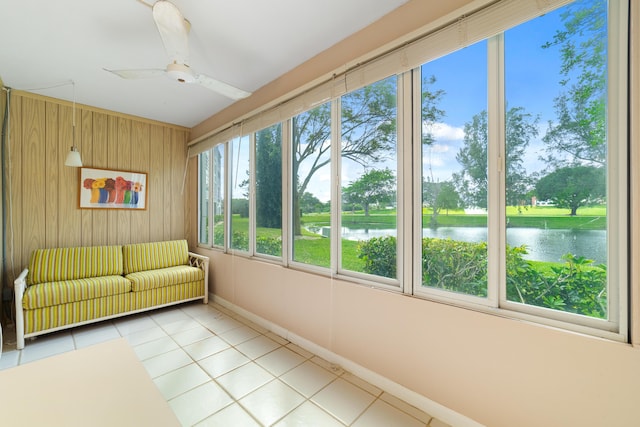 unfurnished sunroom featuring ceiling fan and a water view