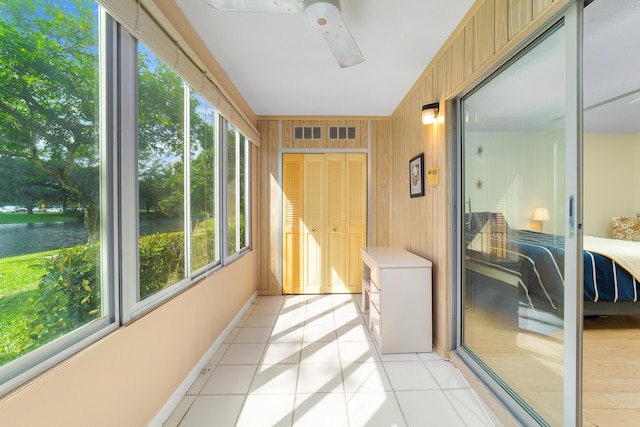 sunroom / solarium with ceiling fan and a water view