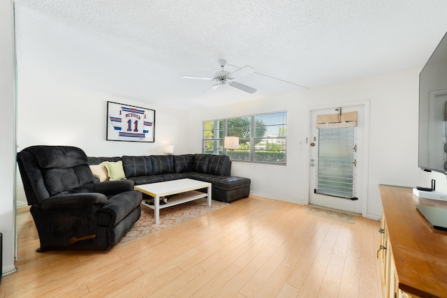 living room featuring ceiling fan, a textured ceiling, and light hardwood / wood-style floors