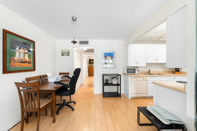 kitchen featuring pendant lighting, white appliances, white cabinetry, and light hardwood / wood-style flooring