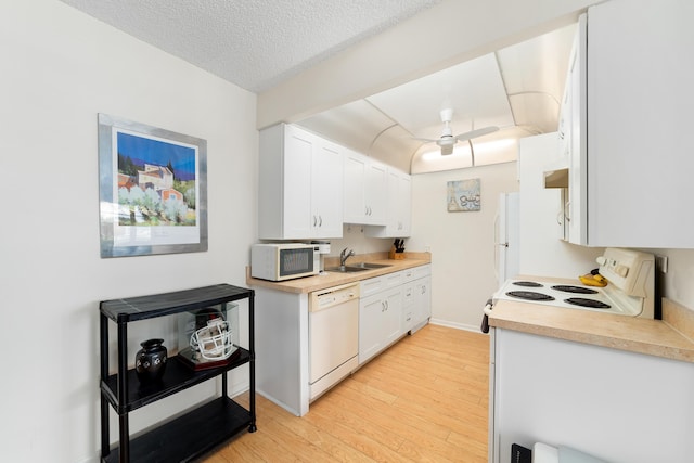 kitchen with sink, a textured ceiling, light hardwood / wood-style flooring, white appliances, and white cabinets