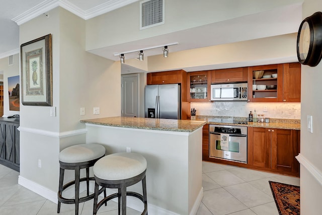 kitchen with stainless steel appliances, tasteful backsplash, light stone counters, and a kitchen bar