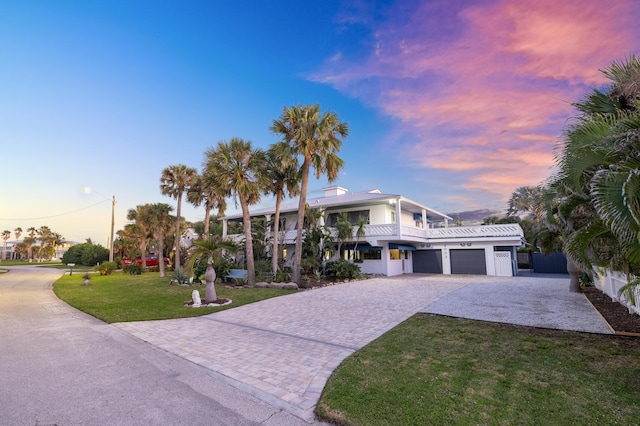 view of front facade with a garage, decorative driveway, and a yard