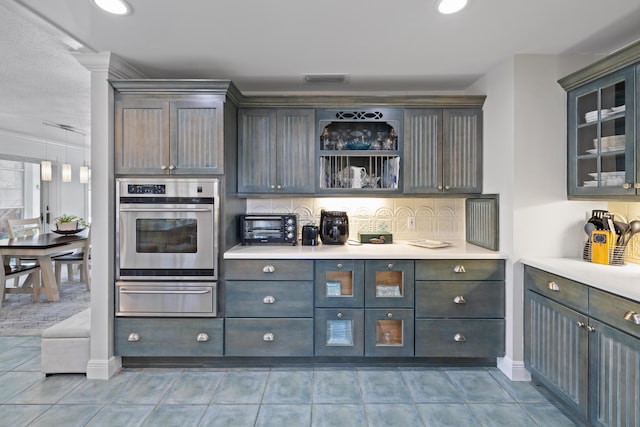 kitchen featuring stainless steel oven, decorative backsplash, and light tile patterned floors