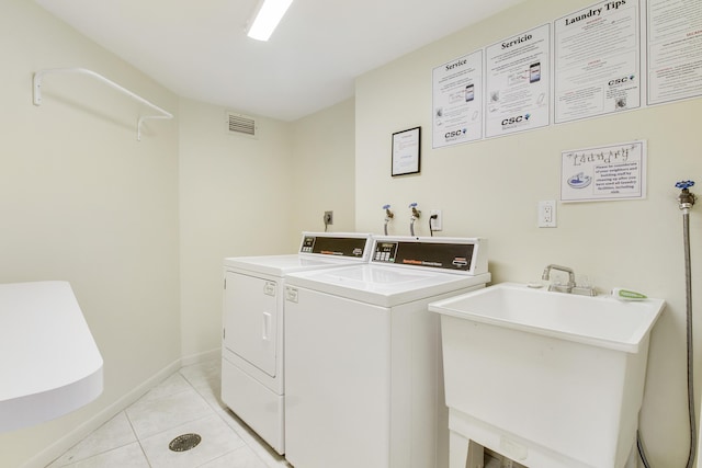 clothes washing area featuring sink, light tile patterned floors, and washer and dryer