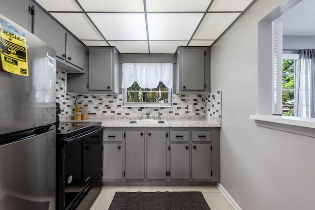 kitchen with black electric range oven, sink, gray cabinets, and stainless steel refrigerator