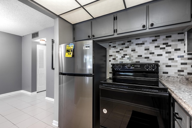 kitchen with black electric range oven, light tile patterned floors, stainless steel refrigerator, gray cabinets, and decorative backsplash