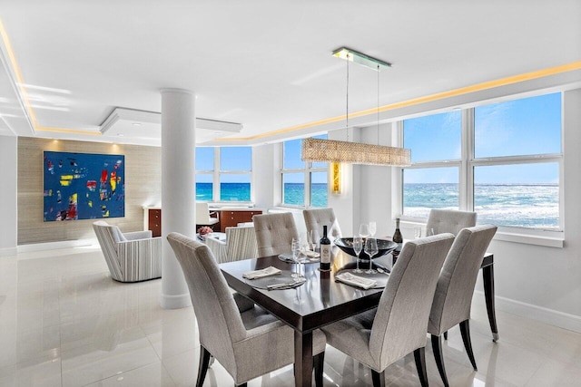 dining room featuring decorative columns, a water view, and light tile patterned floors