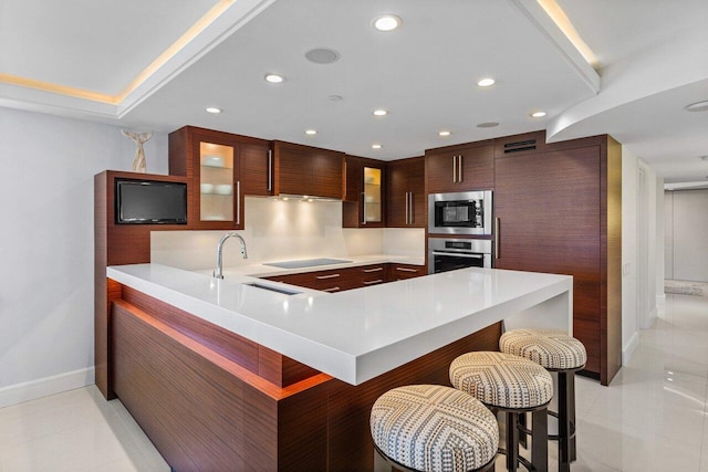 kitchen with sink, a breakfast bar area, light tile patterned floors, kitchen peninsula, and stainless steel appliances