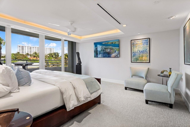 carpeted bedroom with ceiling fan, a raised ceiling, and access to outside