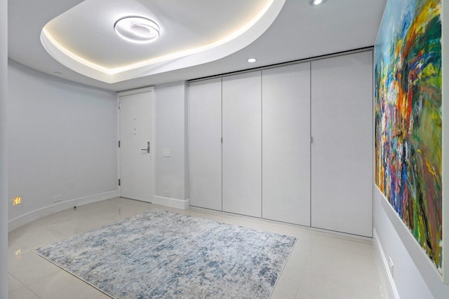 interior space with light tile patterned floors and a tray ceiling