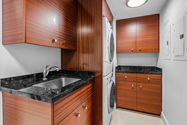 kitchen with sink, dark stone countertops, stacked washer and dryer, light tile patterned floors, and electric panel