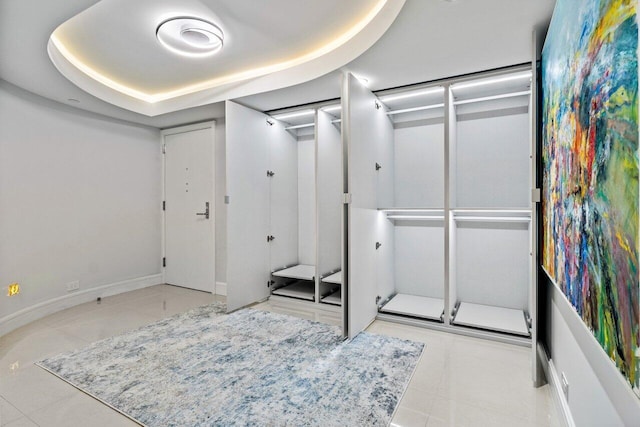 interior space featuring a tray ceiling and light tile patterned floors