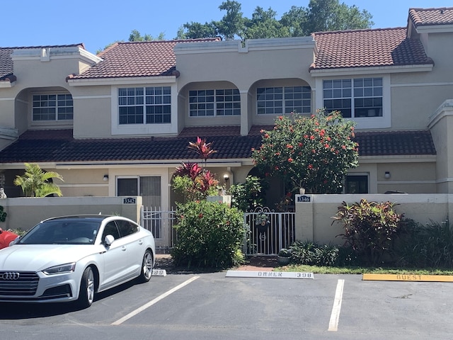 view of front of house featuring a tiled roof, uncovered parking, a fenced front yard, and stucco siding