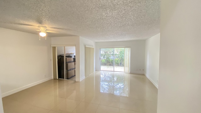 spare room featuring tile patterned flooring, baseboards, and a textured ceiling