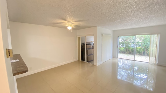 tiled spare room with a textured ceiling, baseboards, and a ceiling fan