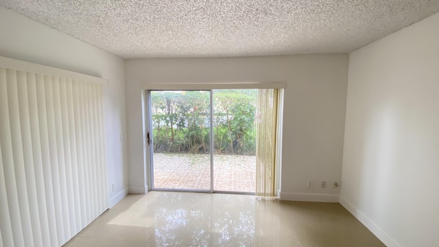 unfurnished room with baseboards and a textured ceiling