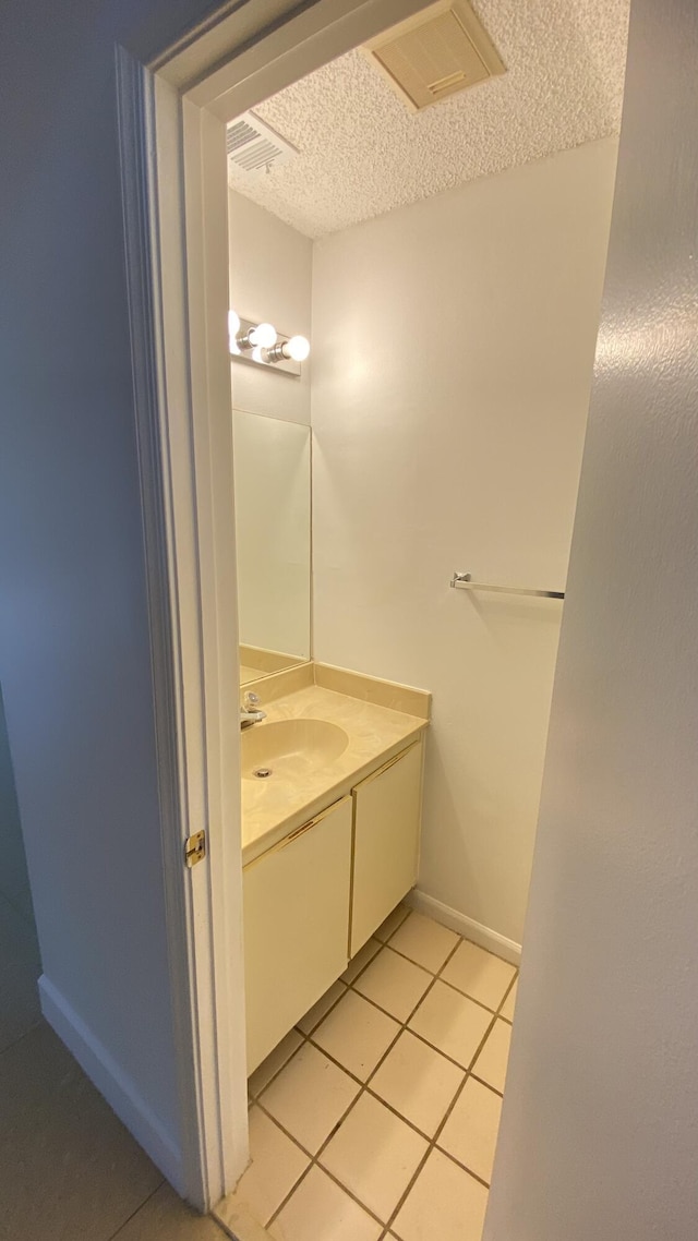 bathroom featuring visible vents, a textured ceiling, tile patterned flooring, baseboards, and vanity