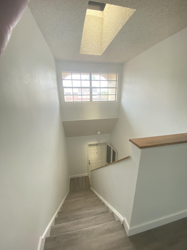 stairway with baseboards, a textured ceiling, and wood finished floors